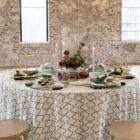 Elegant table setting featuring Emerson Olive linen with a modern wave pattern, surrounded by decorative tableware and floral arrangements, ideal for refined events.