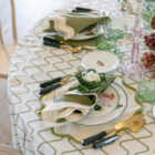Elegant table setting featuring Emerson Olive linen with a medium-scale wave pattern, complemented by green and white dinnerware, cutlery, and decorative elements.