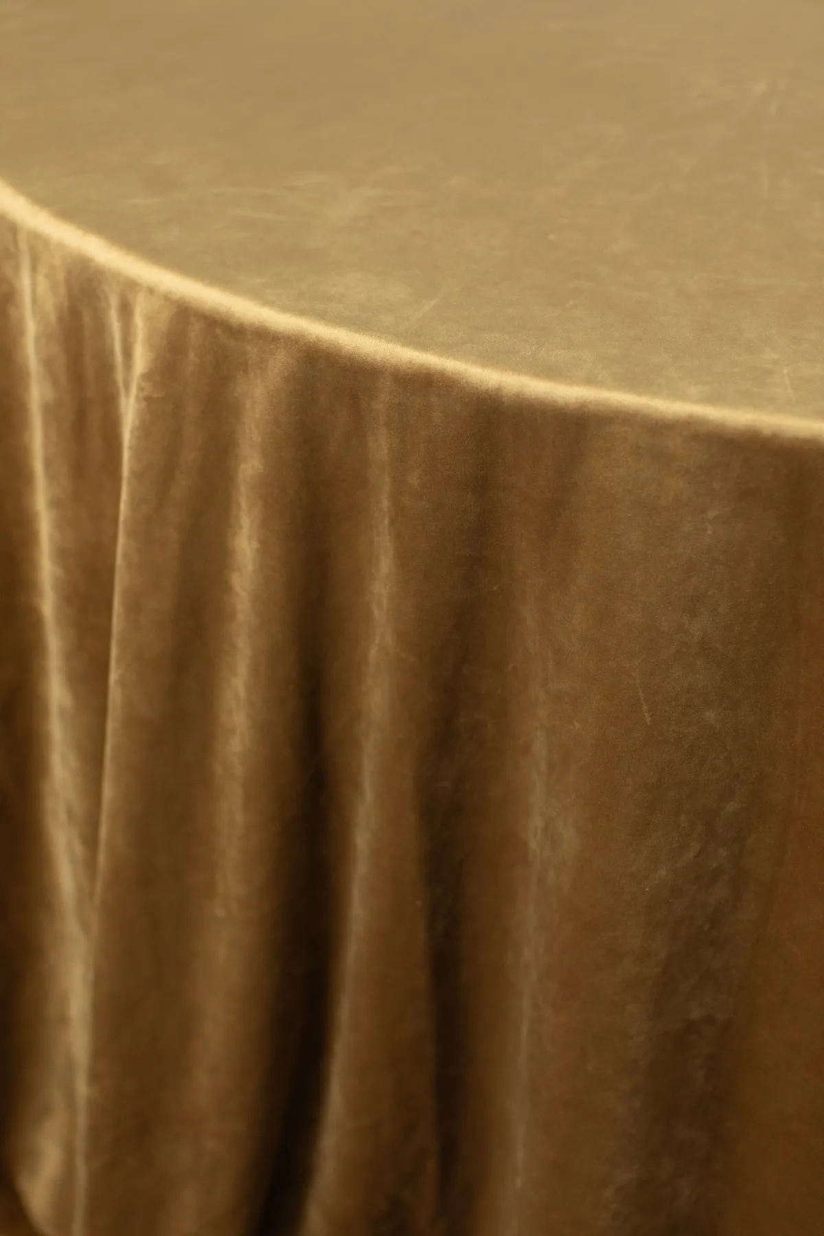 Close-up of rich gold velvet table linen showcasing smooth drape and luxurious sheen.