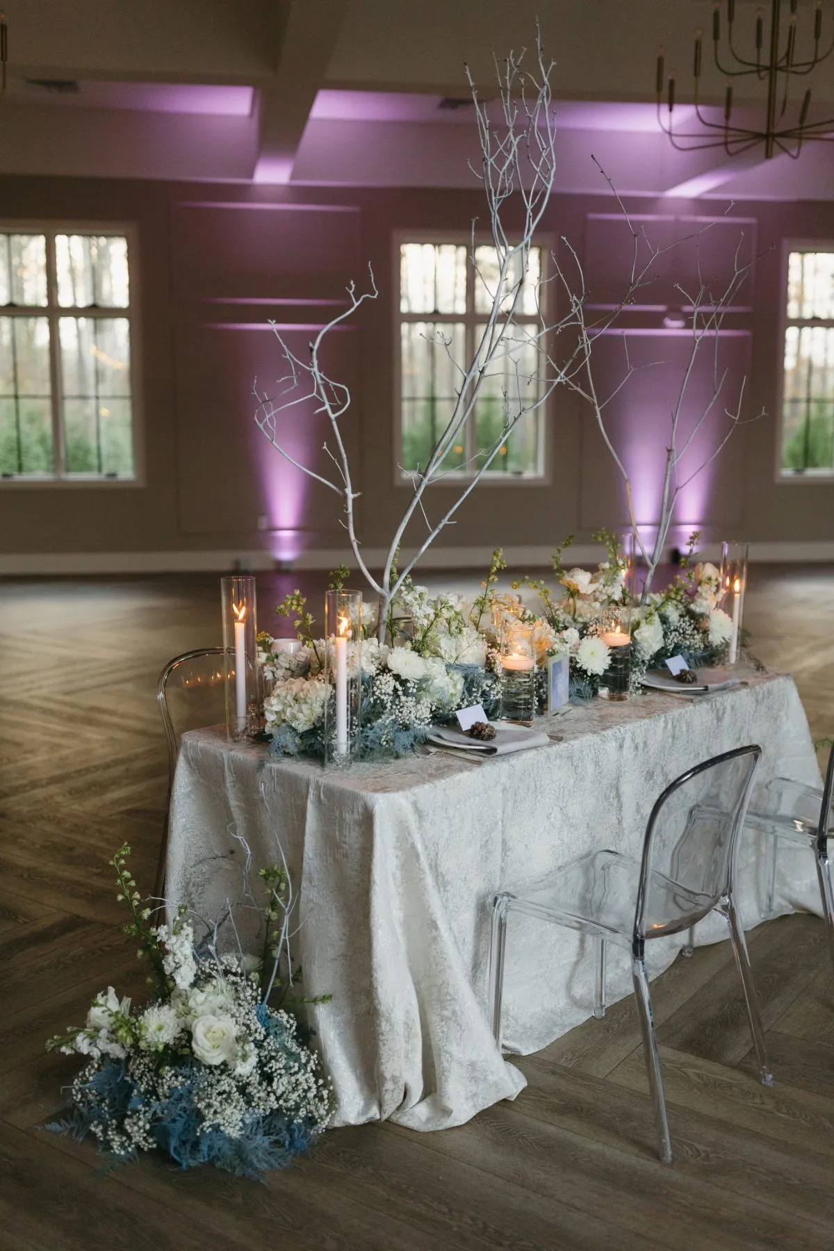 Romantic head table styled with soft ivory linen, candlelight, and abundant florals.