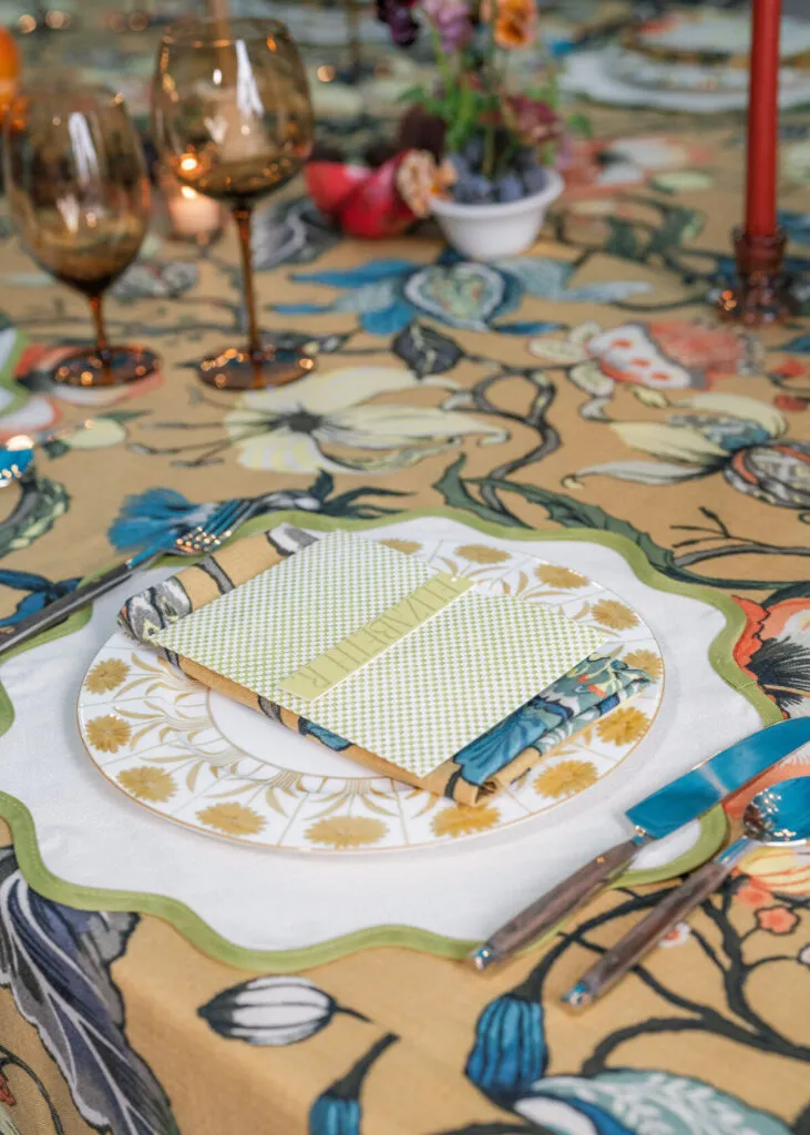 Vibrant floral linen with layered place setting and mixed textures and colors - Curated Linen Collection Elegant table setting featuring layered linens, decorative plates, and stylish glassware, showcasing a controlled color palette and intentional design elements for refined dining experiences.