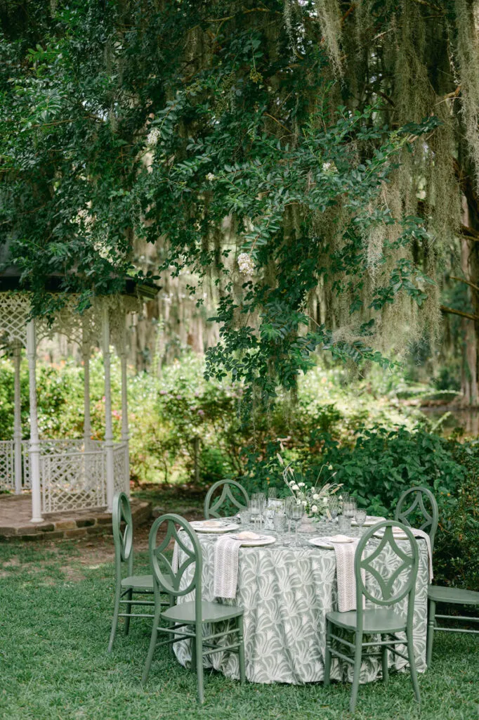 Outdoor table with green patterned linen and matching chairs in garden setting - Curated Linen Collection Outdoor table with green patterned linen and matching chairs in garden setting