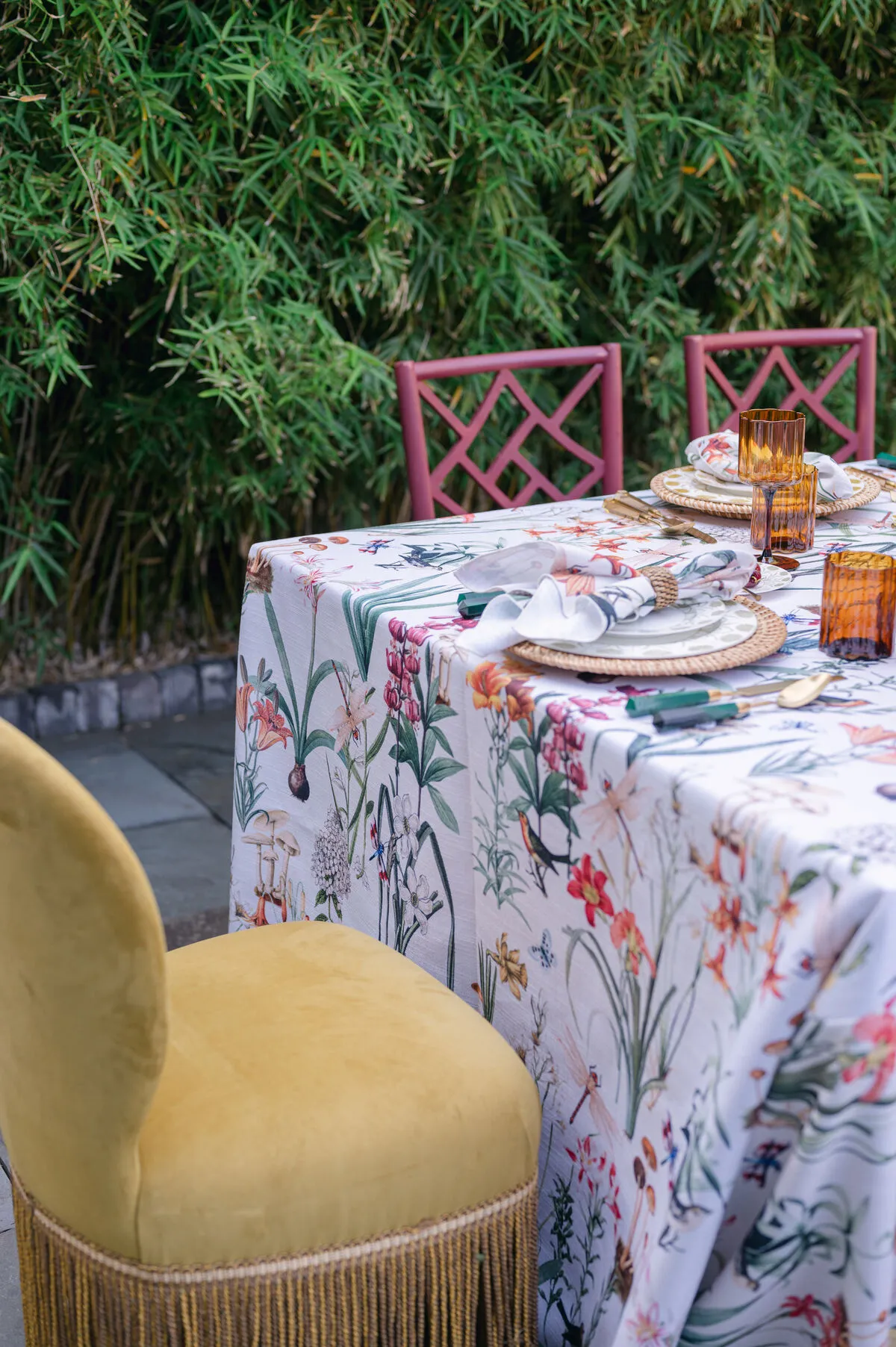 Botanical linen table with amber glassware and colorful chairs outdoors - Curated Linen Collection Botanical linen table with amber glassware and colorful chairs outdoors