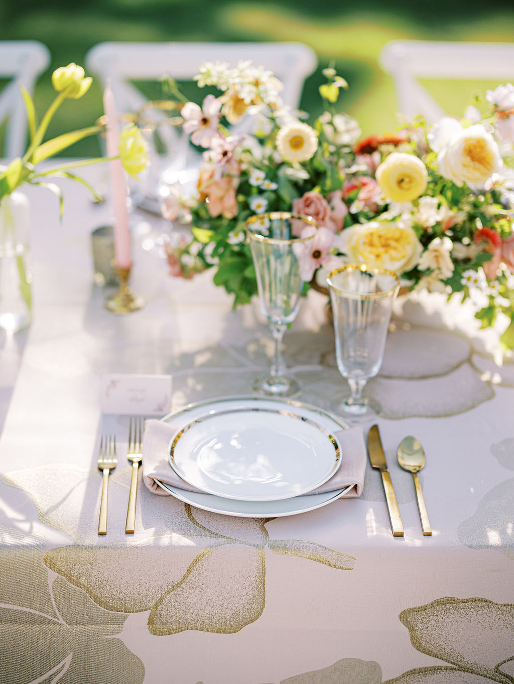 Refined luxury place setting with gold flatware, crystal stemware, soft floral centerpiece, and abstract patterned linen for an upscale reception table. - Curated Linen Collection Refined luxury place setting with gold flatware, crystal stemware, soft floral centerpiece, and abstract patterned linen for an upscale reception table.