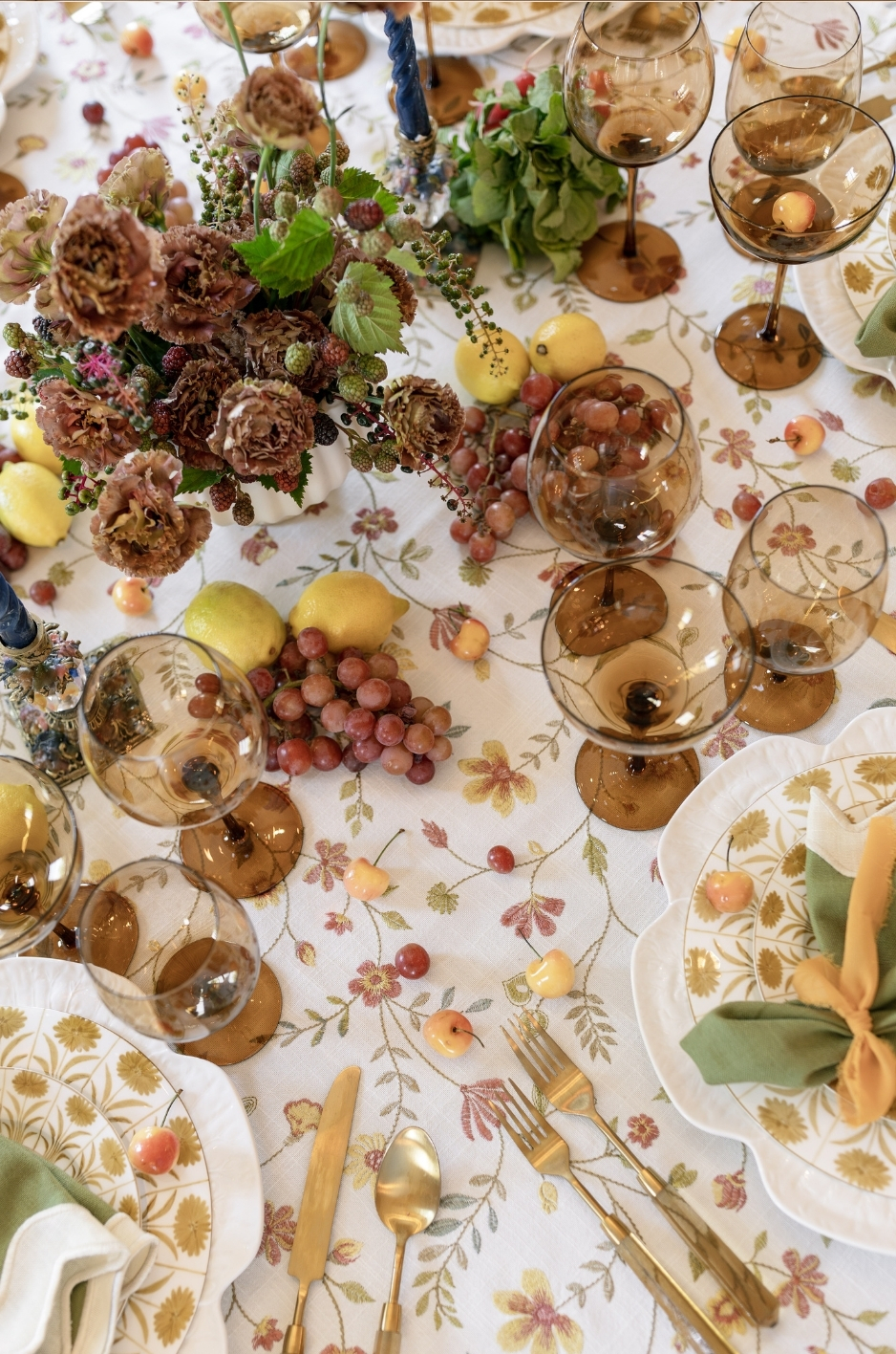 Close-up of floral embroidered table linen with amber stemware, fresh flowers, lemons, grapes, and elegant event table styling. - Curated Linen Collection Close-up of floral embroidered table linen with amber stemware, fresh flowers, lemons, grapes, and elegant event table styling.