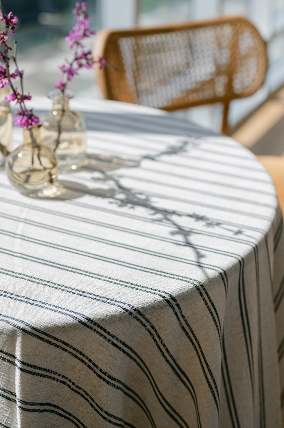 Close-up of striped wedding linen with bud vase and cane-back chair. - Curated Linen Collection Close-up of striped wedding linen with bud vase and cane-back chair.