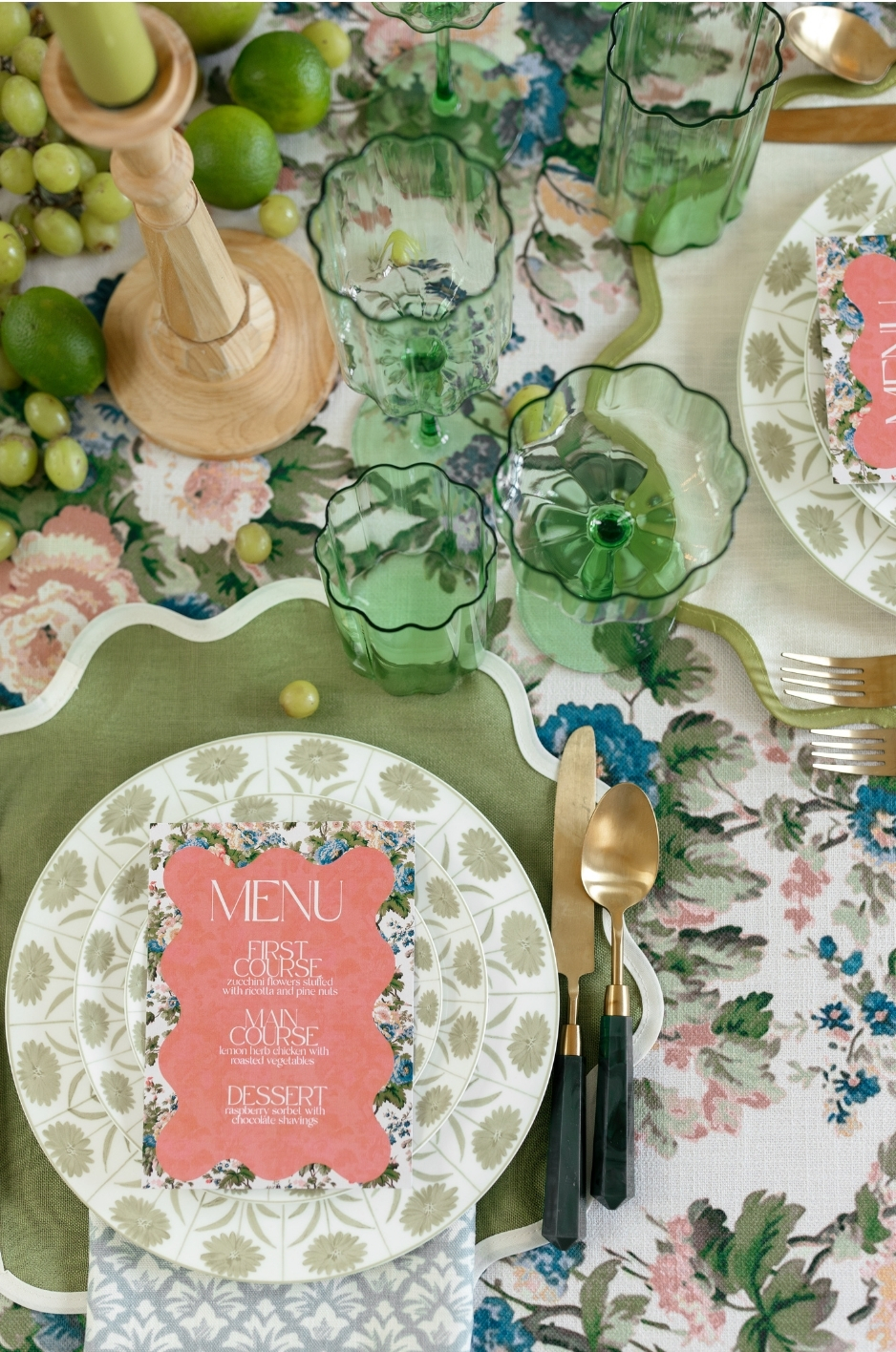 Close-up floral place setting with green glassware, scalloped napkin, gold flatware, and printed menu. - Curated Linen Collection Close-up floral place setting with green glassware, scalloped napkin, gold flatware, and printed menu.