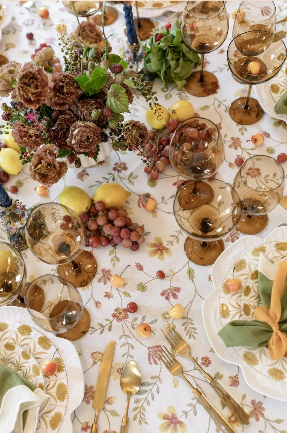 Floral tablecloth with autumn flowers, fruit, and amber goblets - Curated Linen Collection Painterly botanical tablecloth design with floral pattern and autumnal fruit accents, illustrating a non-themed fall