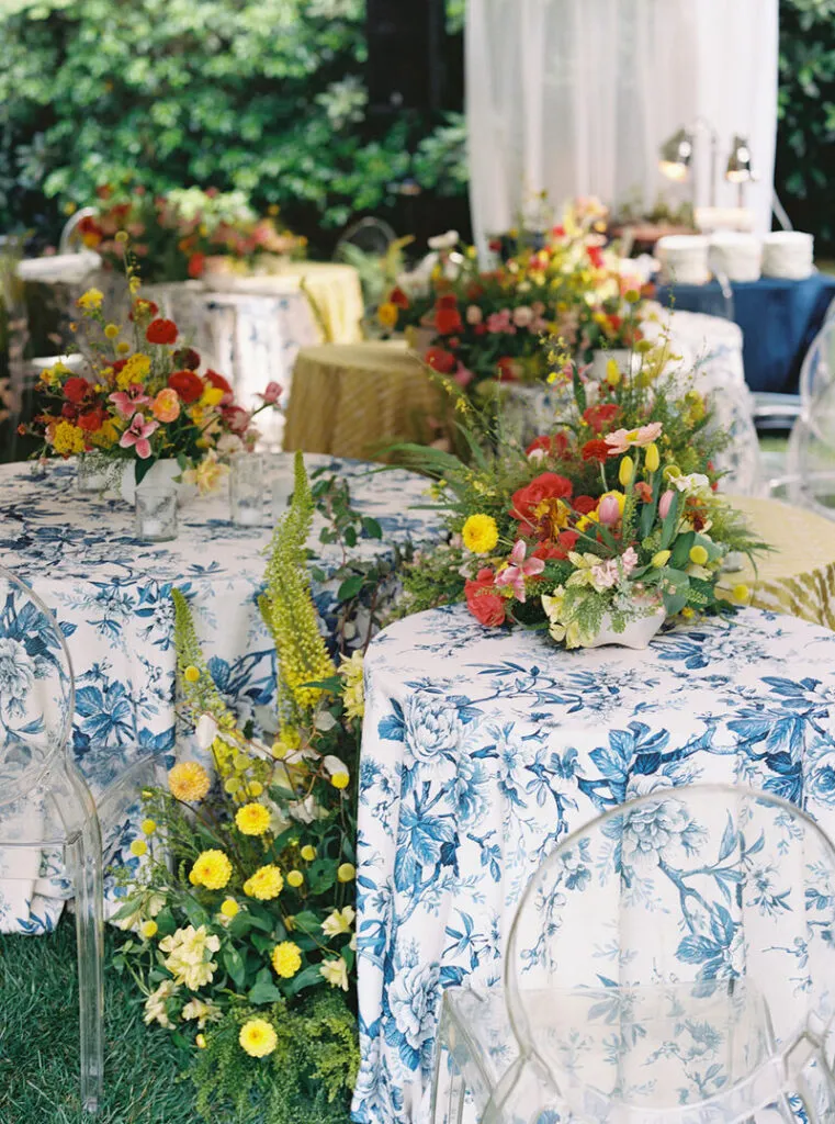 Blue floral table linens with colorful garden centerpieces - Curated Linen Collection Blue and white patterned linens and vibrant floral centerpieces for an elegant estate wedding reception.