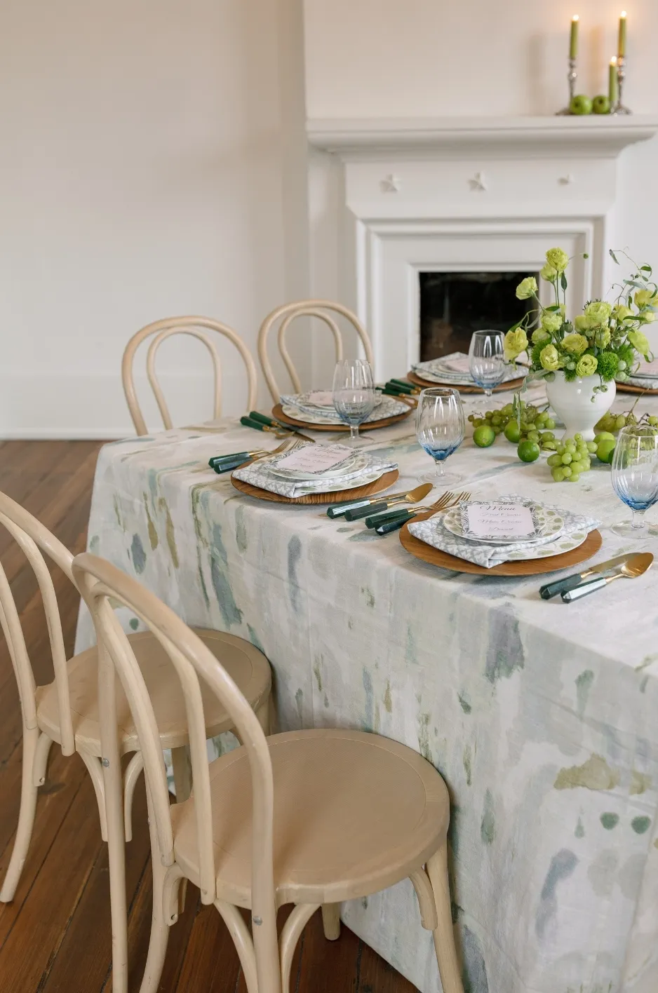 High-end event table with watercolor-style linen, bentwood chairs, layered plates, green glassware, and fresh floral accents - Curated Linen Collection High-end event table with watercolor-style linen, bentwood chairs, layered plates, green glassware, and fresh floral accents
