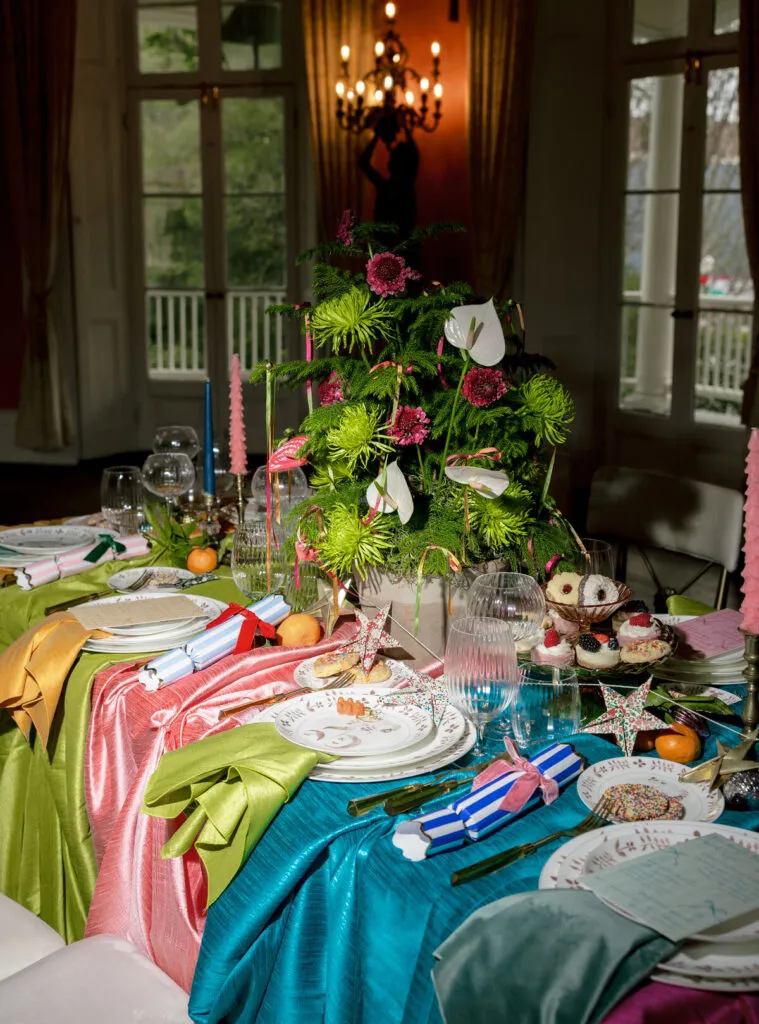 Colorful event tablescape with layered luxury linens, bright table runners, floral decor, and detailed place settings - Curated Linen Collection Luxurious tablescape with layered linens and vibrant floral centerpiece for upscale event design.