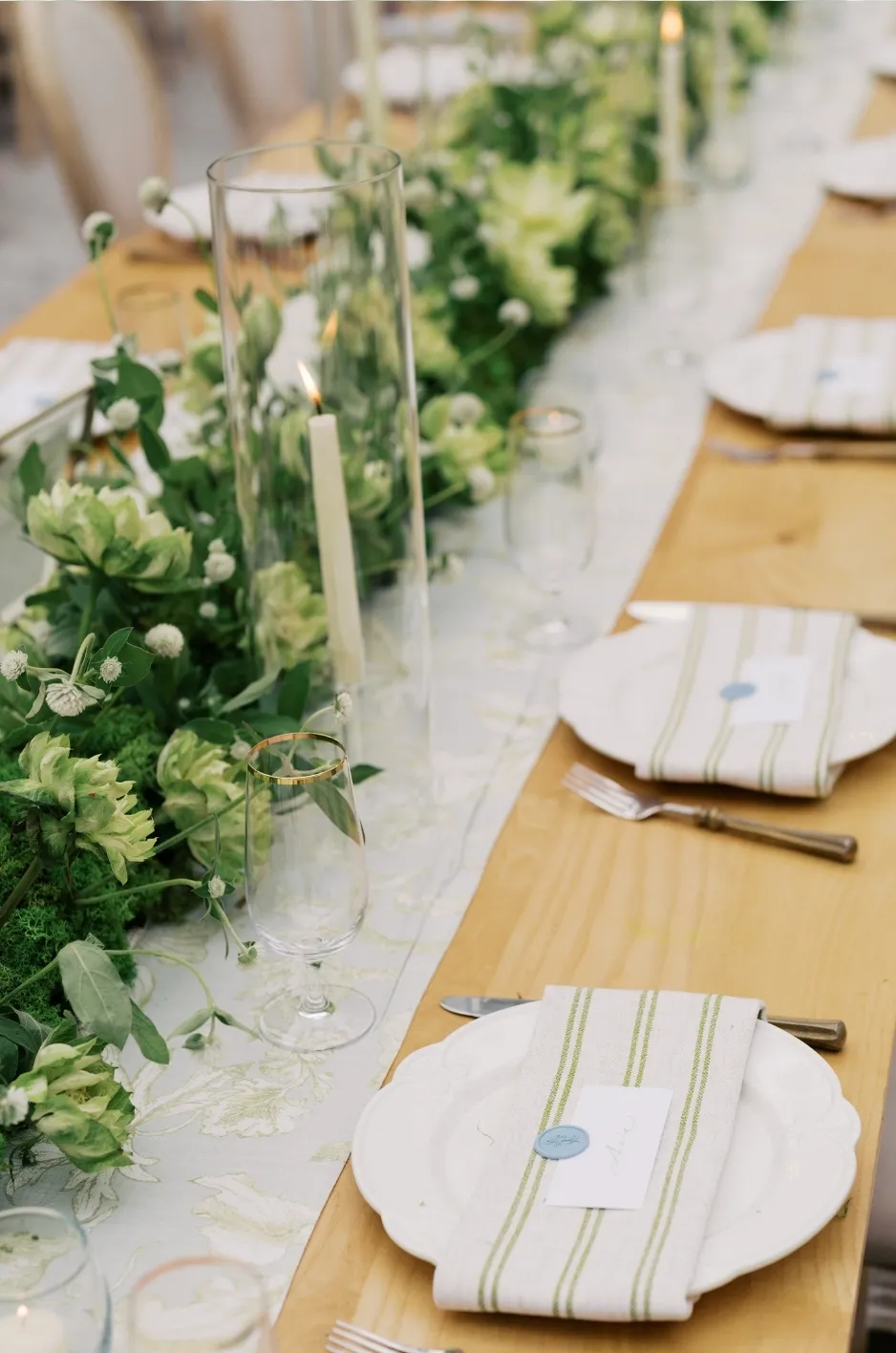 Luxury table runner with floral centerpiece and candles on a long reception table.