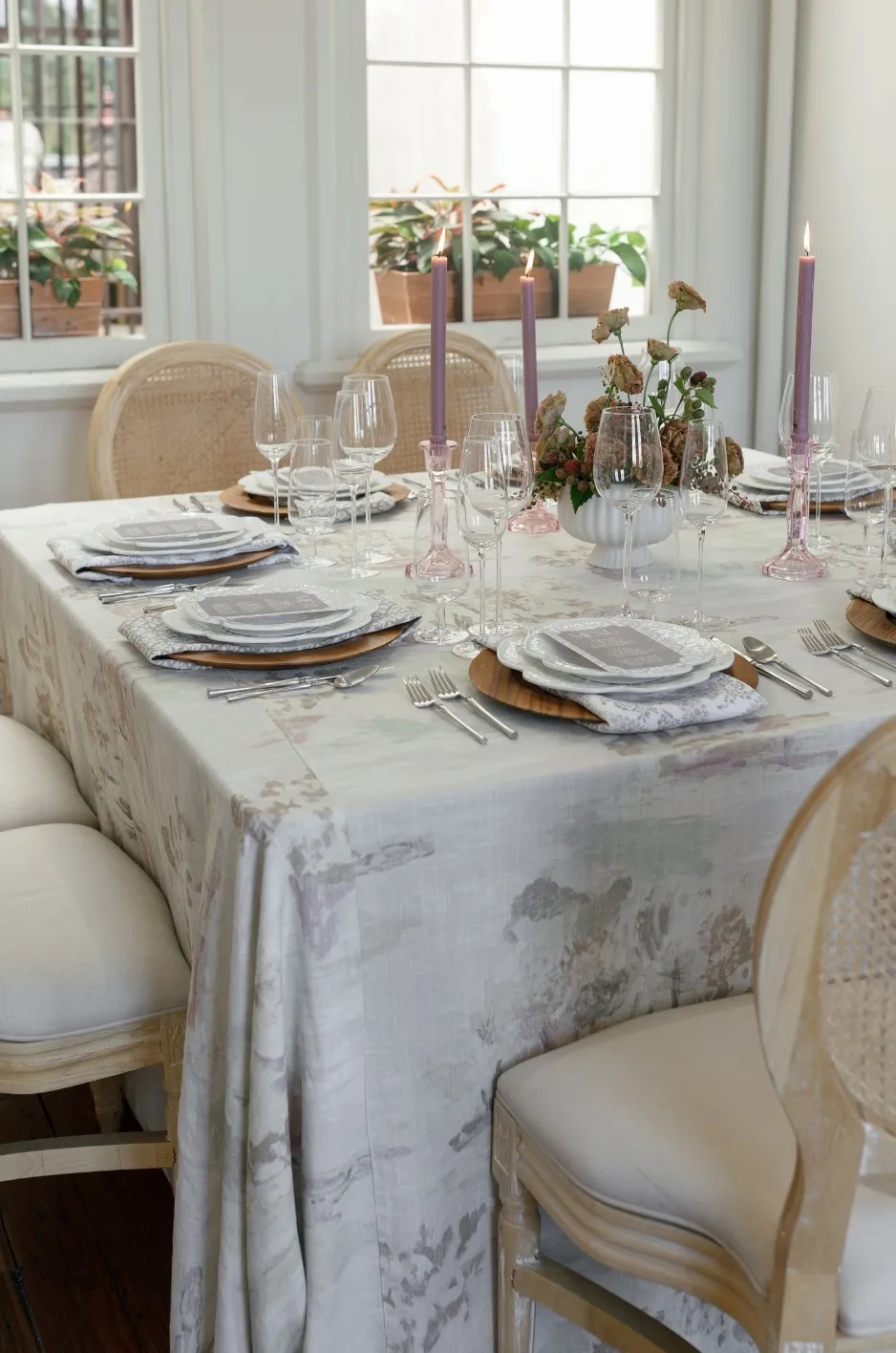 Formal rectangular table with pale patterned linen, purple taper candles, and neutral chairs - Curated Linen Collection Formal rectangular table with pale patterned linen, purple taper candles, and neutral chairs