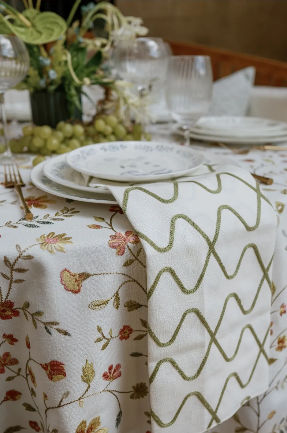 Floral table linen paired with a white and green patterned napkin at a formal gala place setting - Curated Linen Collection Floral table linen paired with a white and green patterned napkin at a formal gala place setting