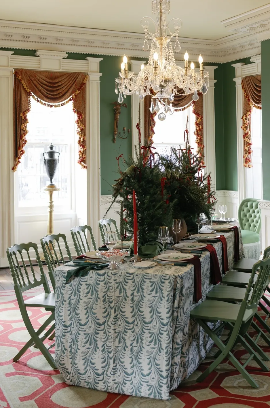Long gala dining table with blue patterned linen, green chairs, chandelier, and dramatic centerpiece - Curated Linen Collection Long gala dining table with blue patterned linen, green chairs, chandelier, and dramatic centerpiece