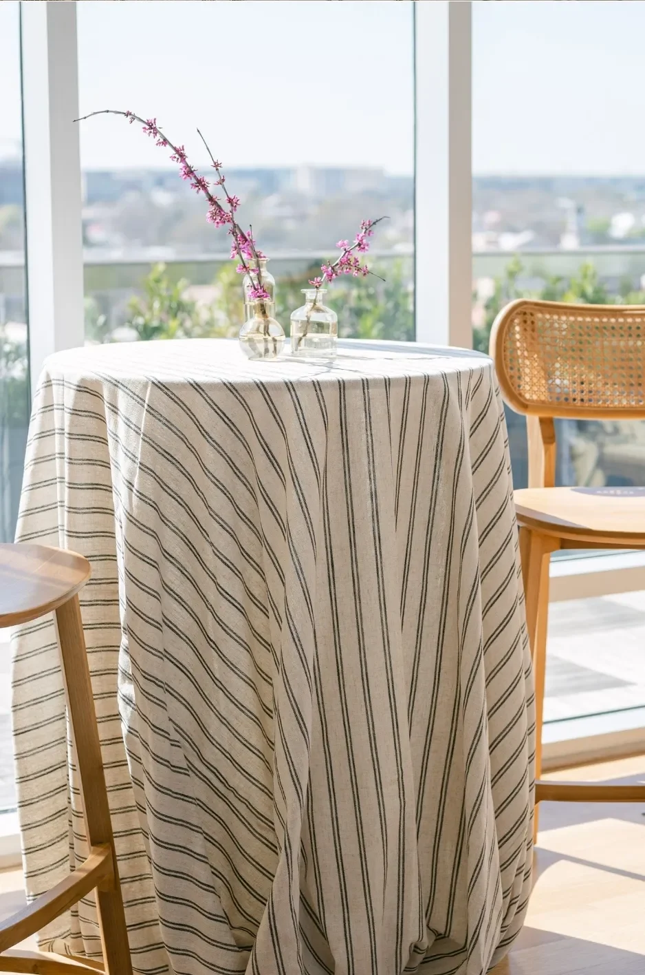 Round cocktail table covered in a cream striped linen with small pink floral arrangements and cane chairs. Round cocktail table covered in a cream striped linen with small pink floral arrangements and cane chairs.