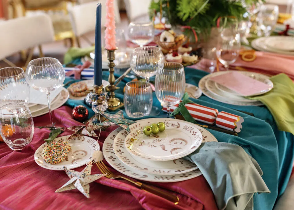 Formal gala tablescape with pink and teal linens, patterned dinnerware, candles, and glassware - Curated Linen Collection Formal gala tablescape with pink and teal linens, patterned dinnerware, candles, and glassware