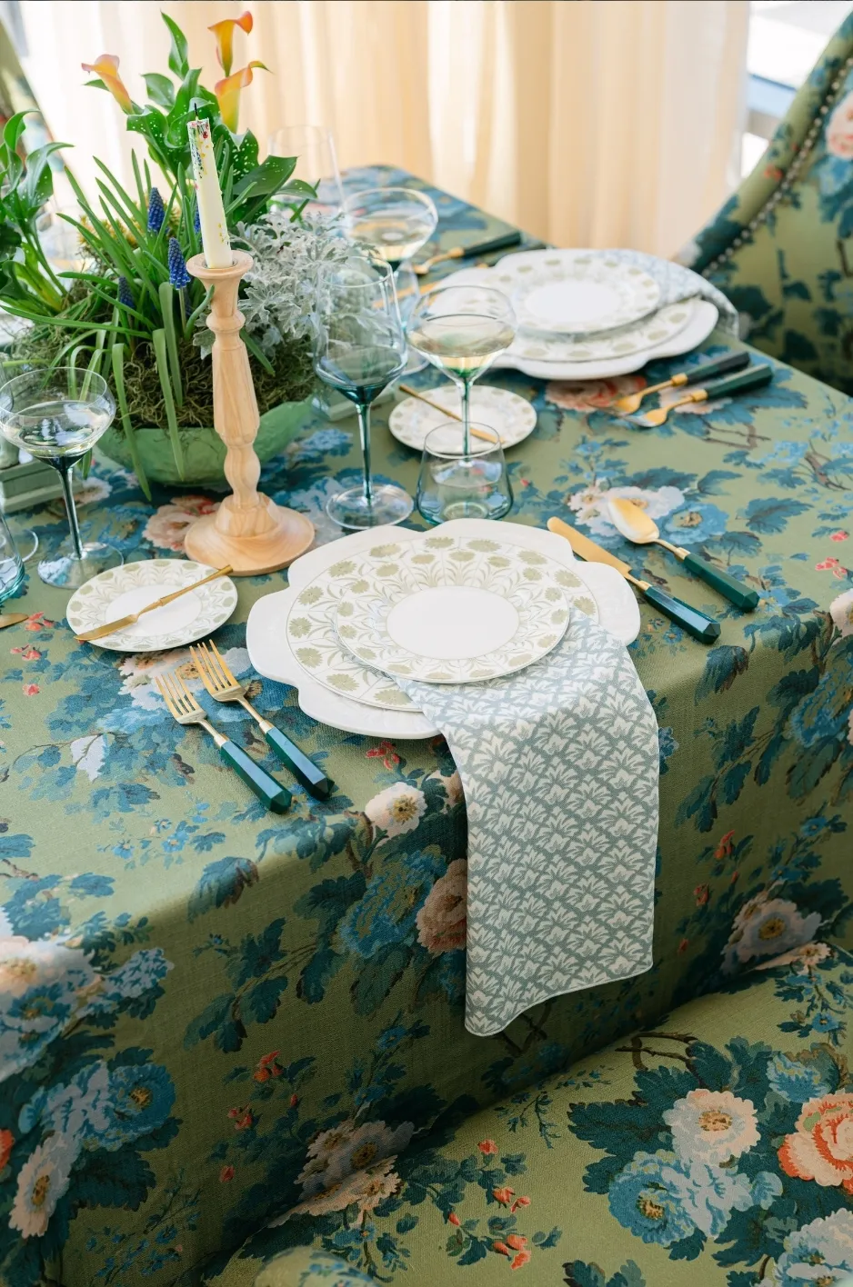 Green botanical tablescape with patterned napkins, white china, green-handled flatware, clear glassware, and tropical flowers. - Curated Linen Collection Green botanical tablescape with patterned napkins, white china, green-handled flatware, clear glassware, and tropical flowers.